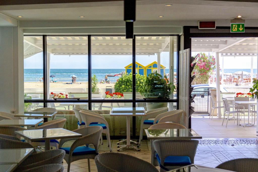 un restaurant avec tables et chaises et vue sur la plage dans l'établissement San Marco, à Marotta