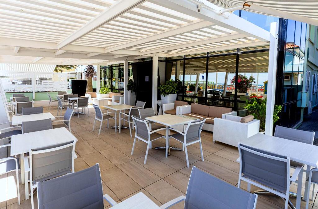 un restaurant avec des tables et des chaises blanches et des fenêtres dans l'établissement San Marco, à Marotta