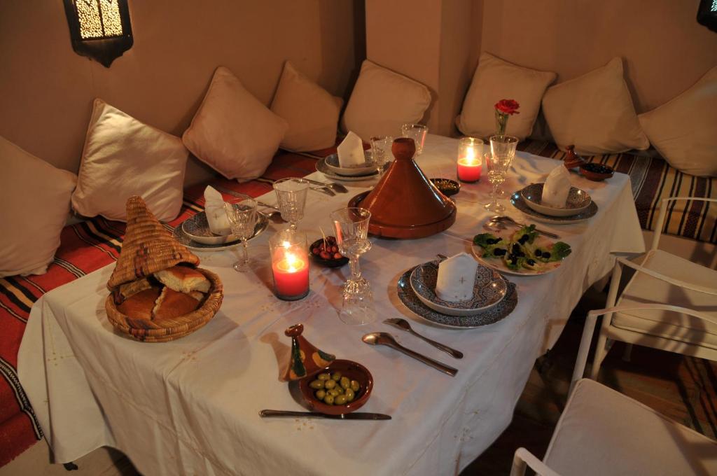 une table avec un tissu de table blanc, de la nourriture et des bougies dans l'établissement Riad Adriana, à Marrakech