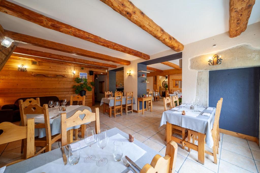 un restaurant avec des tables et des chaises et des plafonds en bois dans l'établissement Auberge des Montauds - Hôtel & Restaurant, à Villard-de-Lans