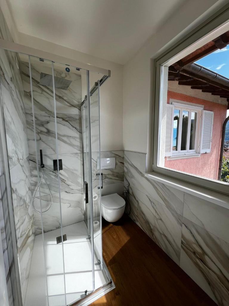une salle de bain avec toilettes et douche en verre dans l'établissement Residence Garden, à Cannobio