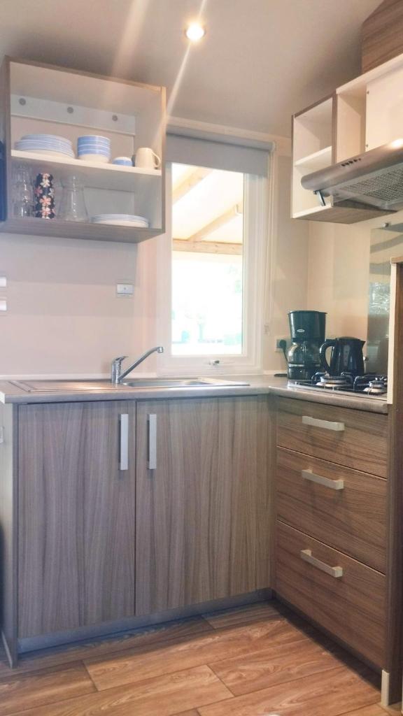 une cuisine avec des armoires en bois et une fenêtre dans l'établissement Mobil Home vue sur le lac dans un camping 4 étoiles à Cadenet, à Cadenet