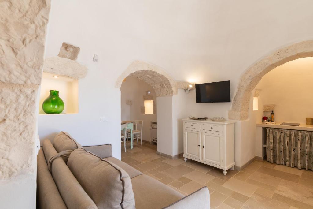 un salon avec un canapé et une télévision dans l'établissement Trullo White Dream con Piscina, à Ostuni