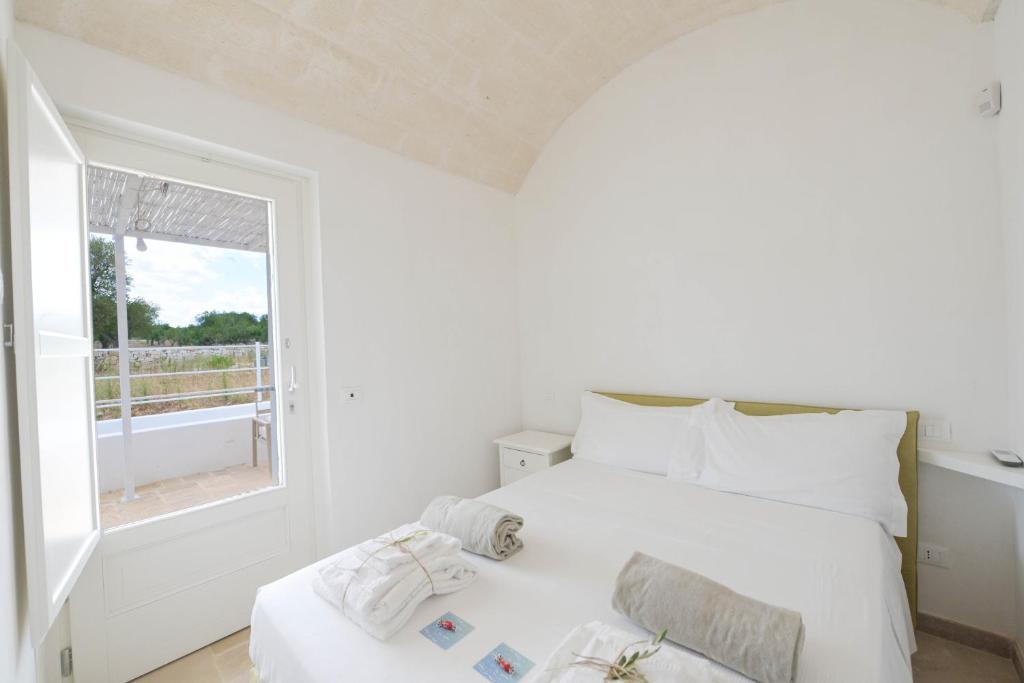 une chambre blanche avec un lit et une fenêtre dans l'établissement Trullo White Dream con Piscina, à Ostuni