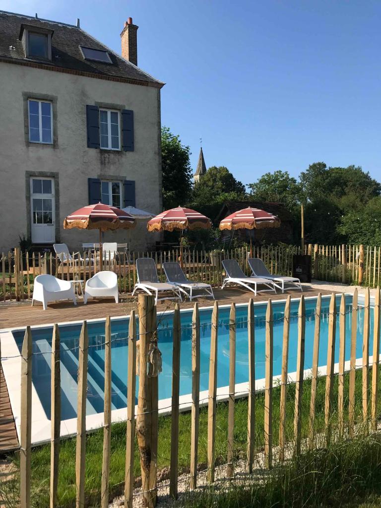 - une piscine en face d'une maison avec des chaises et des parasols dans l'établissement Le Brasseur Logements - Tents, à Saint-Caprais