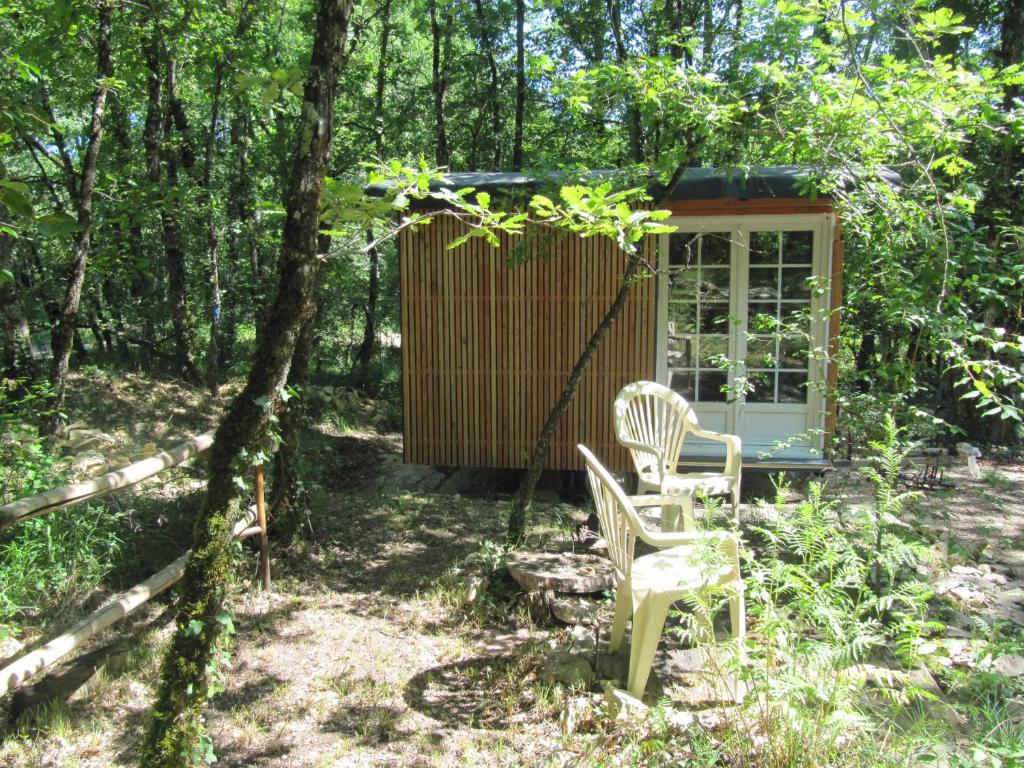 une cabane dans les bois avec deux chaises et un arbre dans l'établissement L'échappatoire, à Masquières