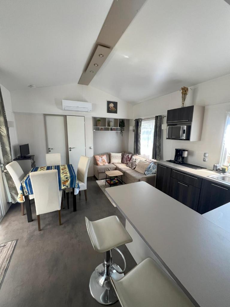 une cuisine et un salon avec une table et des chaises dans l'établissement Camping Del Mar 125, Mobile Home O'Hara Supérieur 1060, 3 chambres, 40 m2, Terrasse, à Argelès-sur-Mer