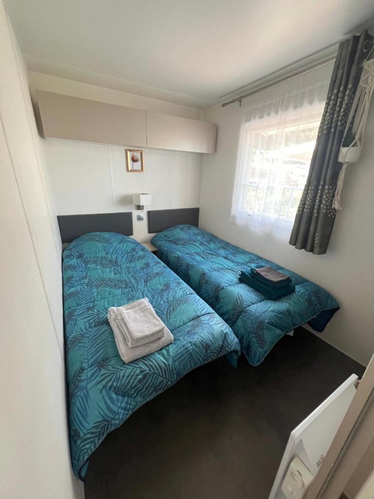 une petite chambre avec deux lits et une fenêtre dans l'établissement Camping Del Mar 125, Mobile Home O'Hara Supérieur 1060, 3 chambres, 40 m2, Terrasse, à Argelès-sur-Mer 20 autres photos