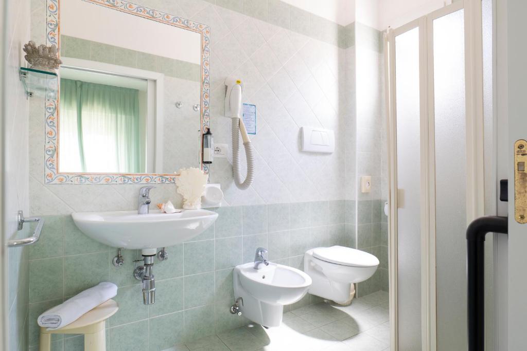 une salle de bain avec un lavabo, des toilettes et un miroir dans l'établissement Hotel Negresco, à Riccione