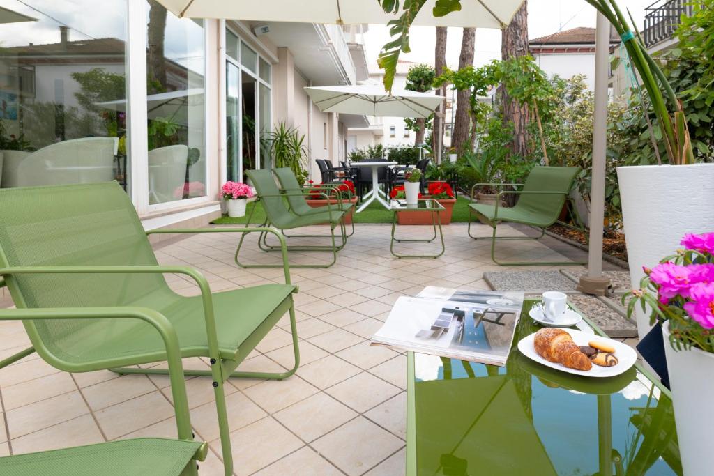 un patio avec des chaises et une assiette de nourriture sur une table dans l'établissement Hotel Negresco, à Riccione