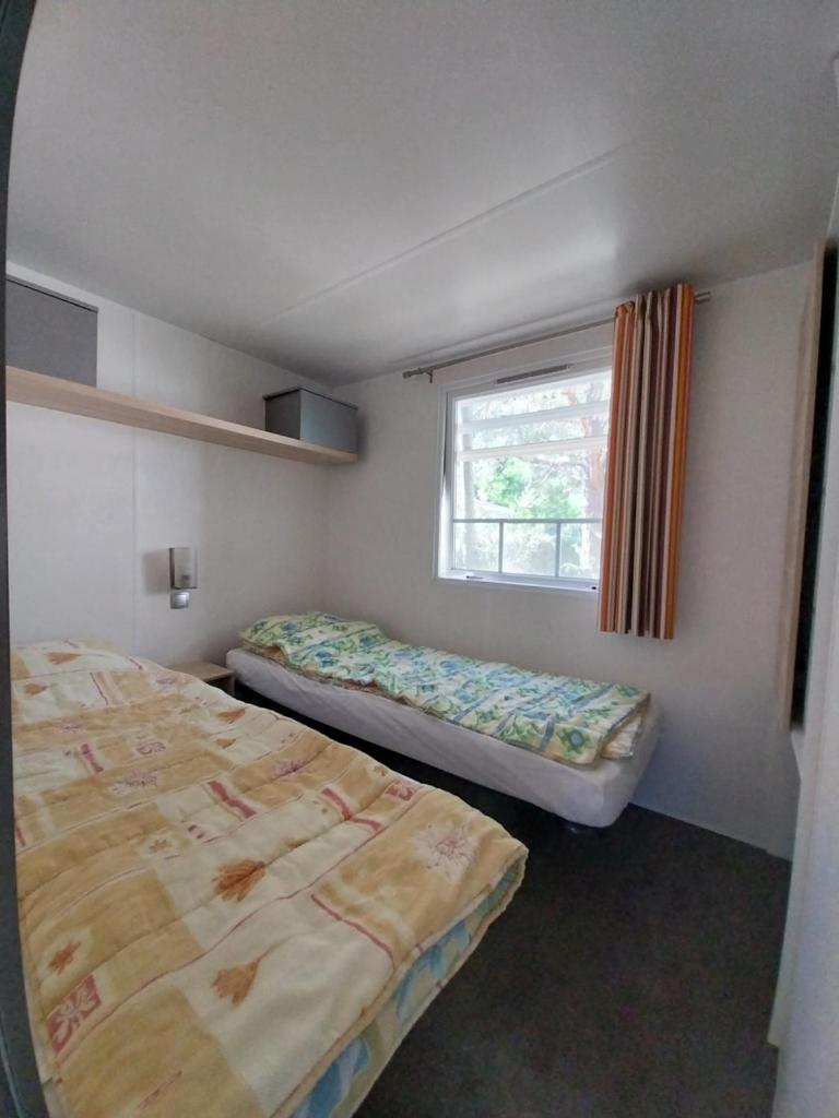 une petite chambre avec deux lits et une fenêtre dans l'établissement Camping Sainte Victoire, à Beaurecueil