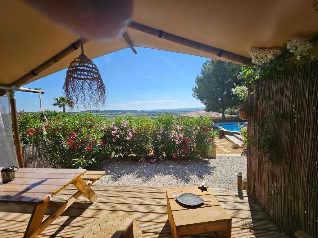une terrasse en bois avec une table, des chaises et des fleurs dans l'établissement DOMAINE DU CHENE, à Campagnan
