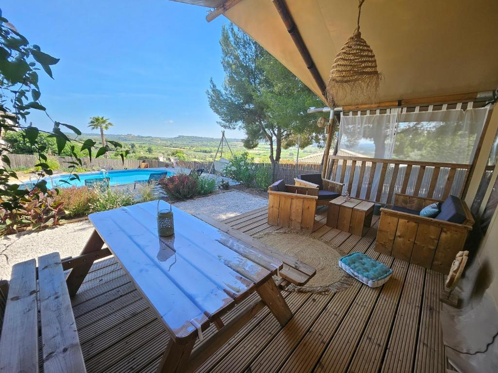 une terrasse en bois avec une table et des chaises ainsi qu'une piscine dans l'établissement DOMAINE DU CHENE, à Campagnan
