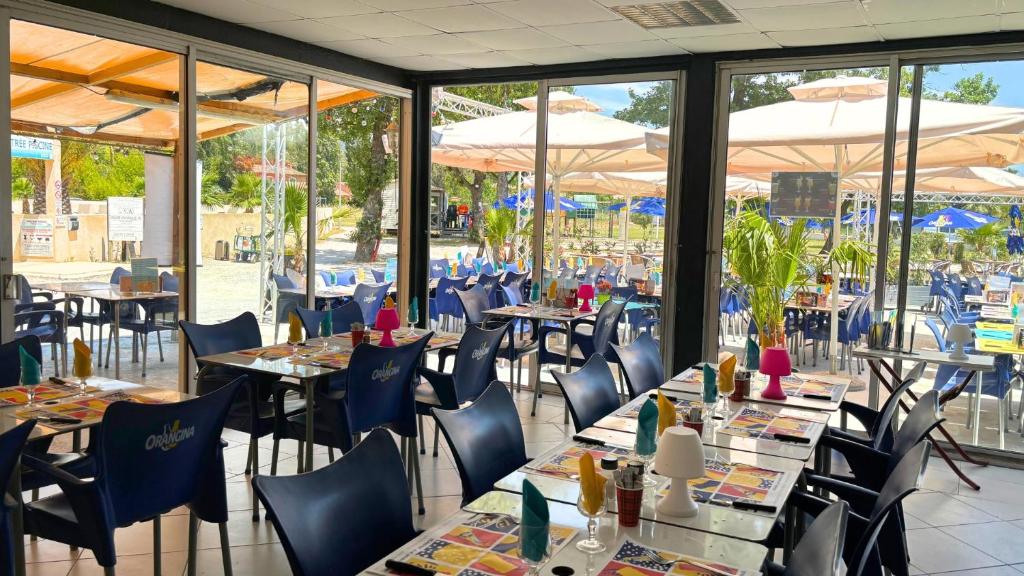 - une salle à manger avec des tables, des chaises et des parasols dans l'établissement Camping Domaine Du Golfe De Saint Tropez, à Grimaud
