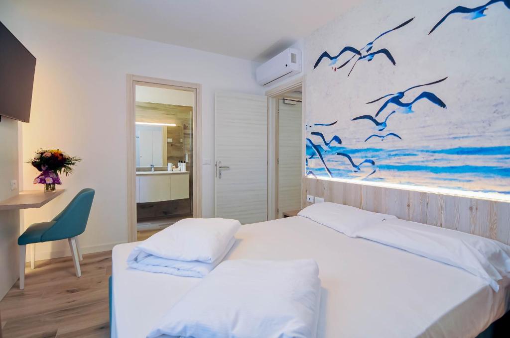 une chambre avec deux lits et un tableau d'oiseaux dans l'établissement Marina Suites & Apartments 4 stelle S, à Caorle 34 autres photos