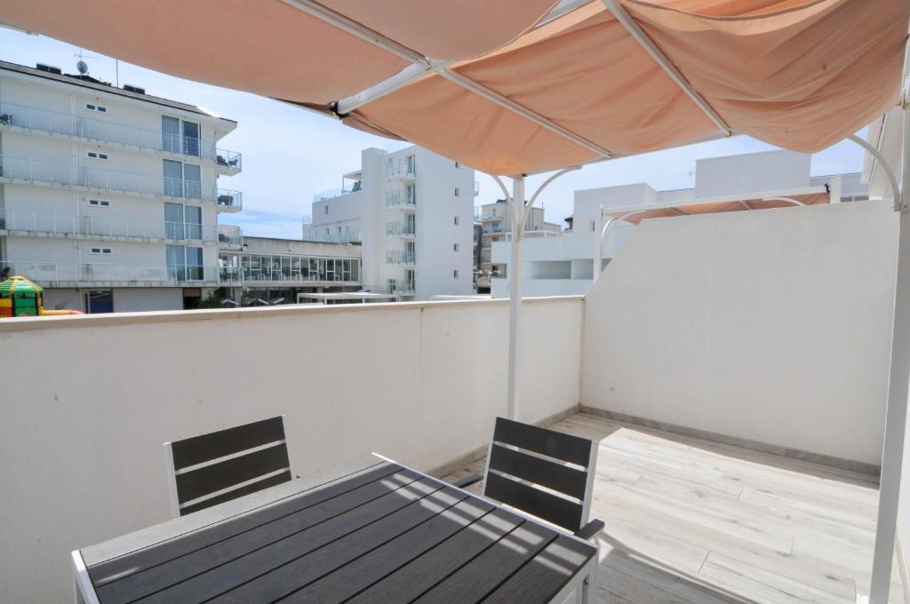 une table et des chaises sur un balcon avec un parasol dans l'établissement Marina Suites & Apartments 4 stelle S, à Caorle
