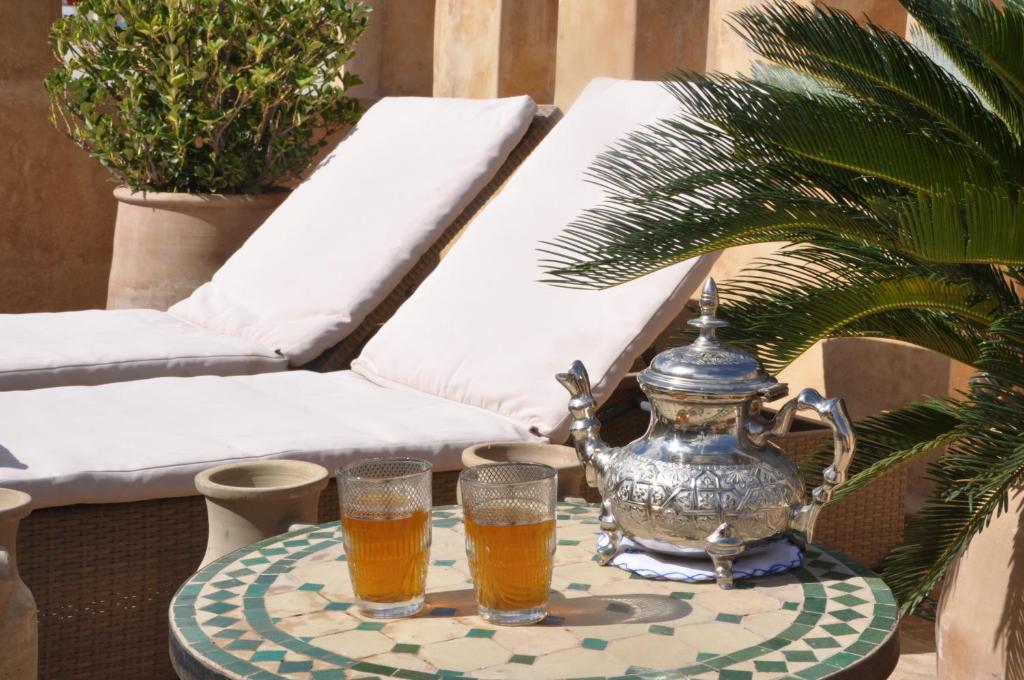 - deux verres de bière sur une table avec une bouilloire dans l'établissement Riad Adarissa, à Fès