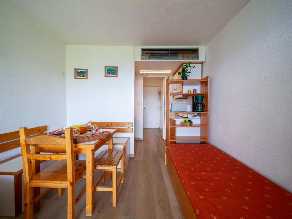 une salle à manger avec une table, des chaises et un tapis rouge dans l'établissement Apartment Pegase Phenix-1 by Interhome, au Corbier