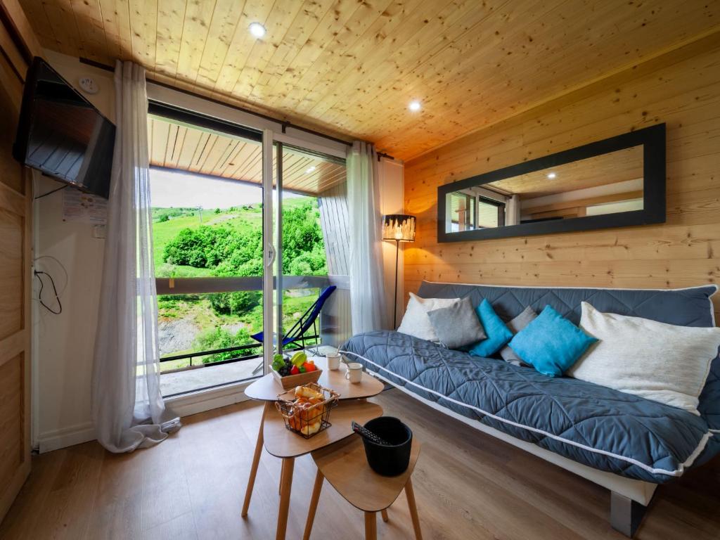un salon avec un canapé bleu et une grande fenêtre dans l'établissement Apartment Pegase Phenix-71 by Interhome, au Corbier