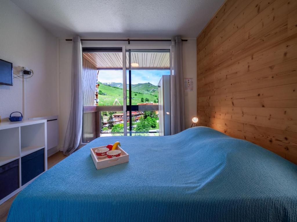 une chambre avec un lit bleu et une grande fenêtre dans l'établissement Apartment Pegase Phenix-71 by Interhome, au Corbier