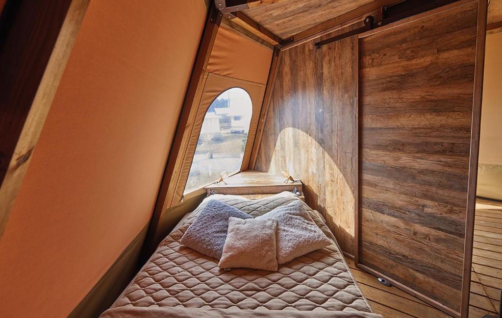 un petit lit dans une chambre avec une fenêtre dans l'établissement Lodge Tipi, L'Indienne, à Arc-et-Senans
