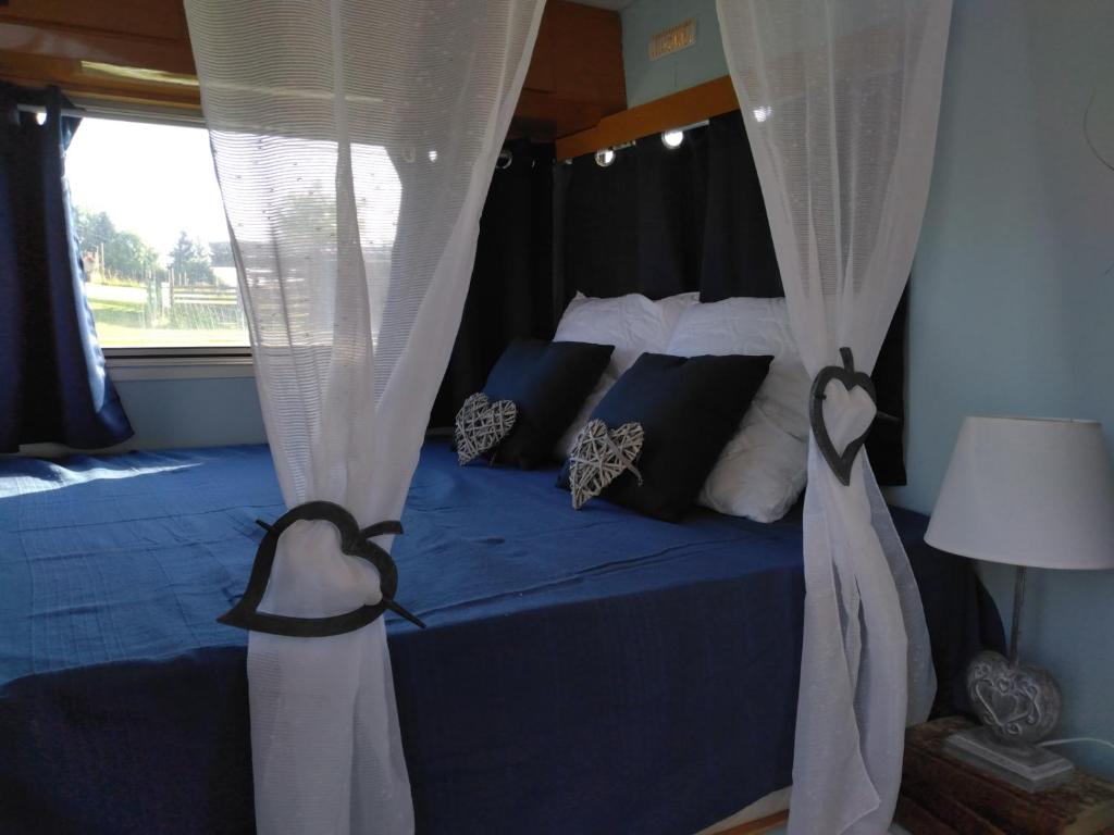- une chambre avec un lit avec des rideaux et une fenêtre dans l'établissement Caravane Seventies avec jacuzzi, à Lapalisse