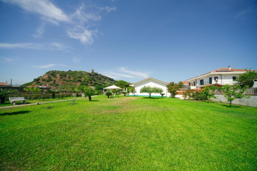 un grand jardin verdoyant avec une colline en arrière-plan dans l'établissement Villa Maredona, à Ascea