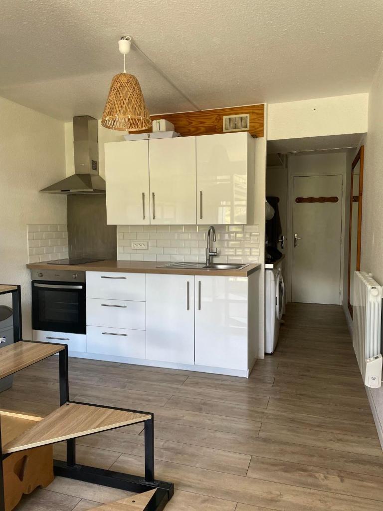 une cuisine avec des armoires blanches et une table à l'intérieur dans l'établissement Appartement au pied des pistes, au Corbier
