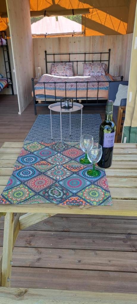 - une table avec des verres à vin et un lit dans une chambre dans l'établissement Lodge Safari tent, à Camurac
