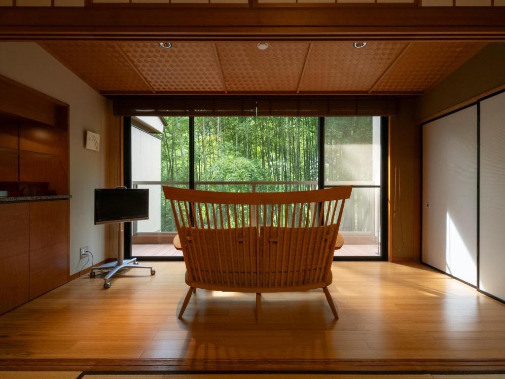 une chaise dans un salon avec une grande fenêtre dans l'établissement Kuriya Yasohachi, à Kaga 19 autres photos
