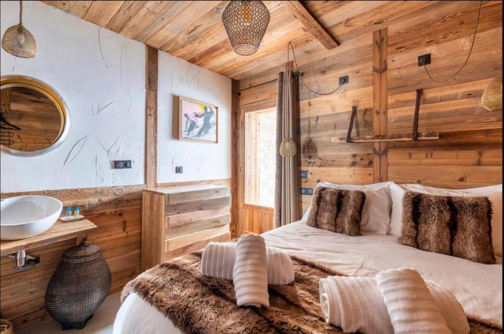 - une chambre dotée de murs en bois, d'un lit et d'un lavabo dans l'établissement Chalet Le Perchoir, Spa, Sauna, sur les pistes, à Villard-Reculas