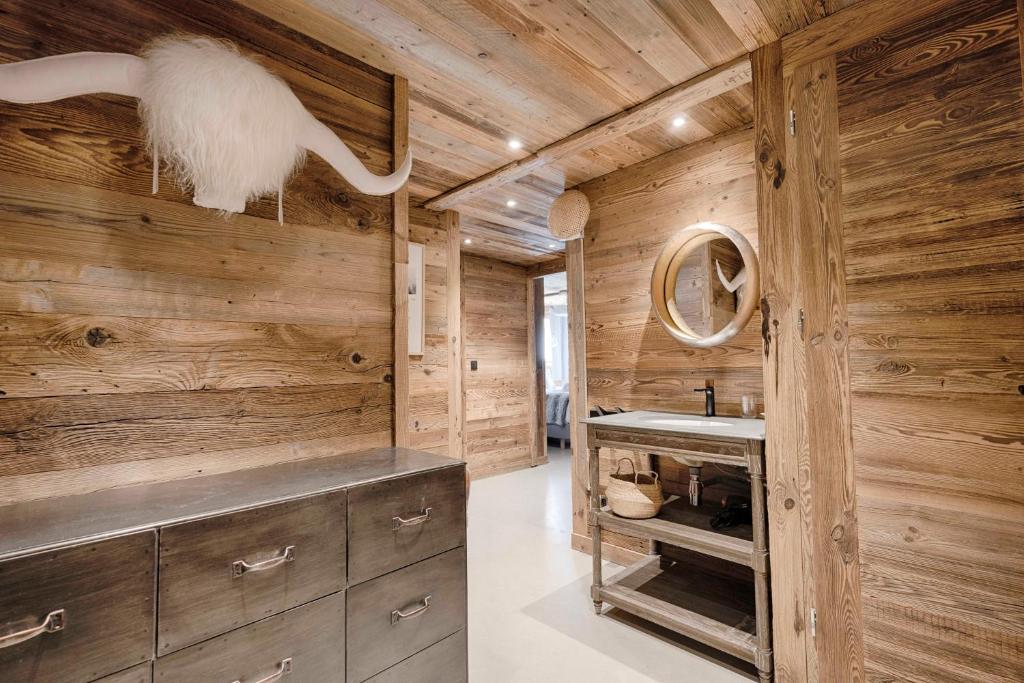 La salle de bains est pourvue de murs en bois et d'un lavabo. dans l'établissement Chalet Le Perchoir, Spa, Sauna, sur les pistes, à Villard-Reculas