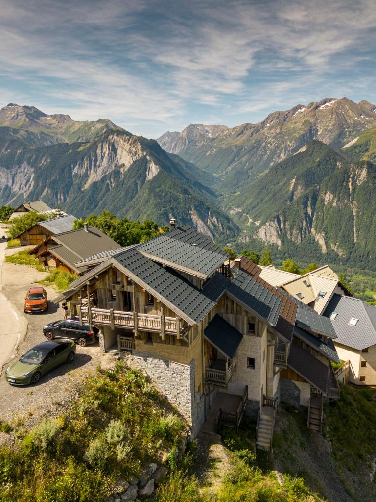 une maison sur une colline avec des montagnes en arrière-plan dans l'établissement Chalet Le Perchoir, Spa, Sauna, sur les pistes, à Villard-Reculas