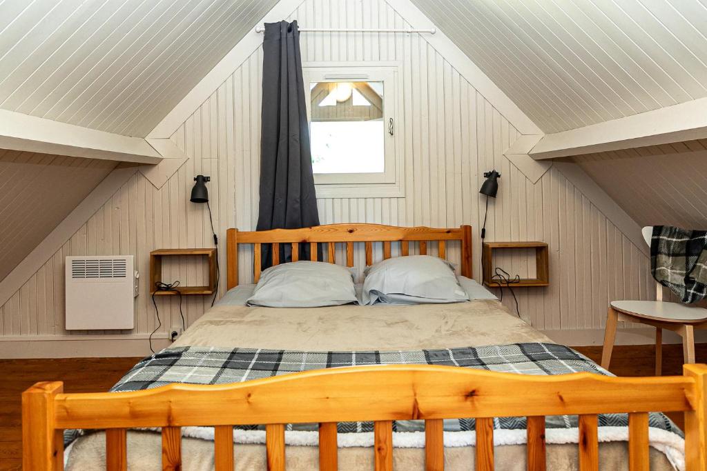 - une chambre mansardée avec un lit en bois dans l'établissement Domaine de Guillaume, à Auquainville