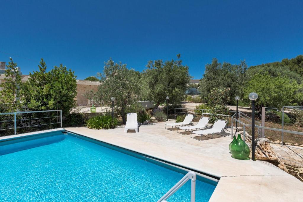 - une piscine avec des chaises longues à côté dans l'établissement Trullo Il Cavaliere by BarbarHouse, à Padresergio