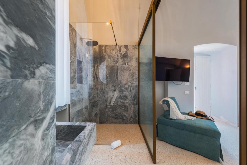 une salle de bain avec une douche en verre avec un canapé vert dans l'établissement Imperial Paradise, à Monopoli