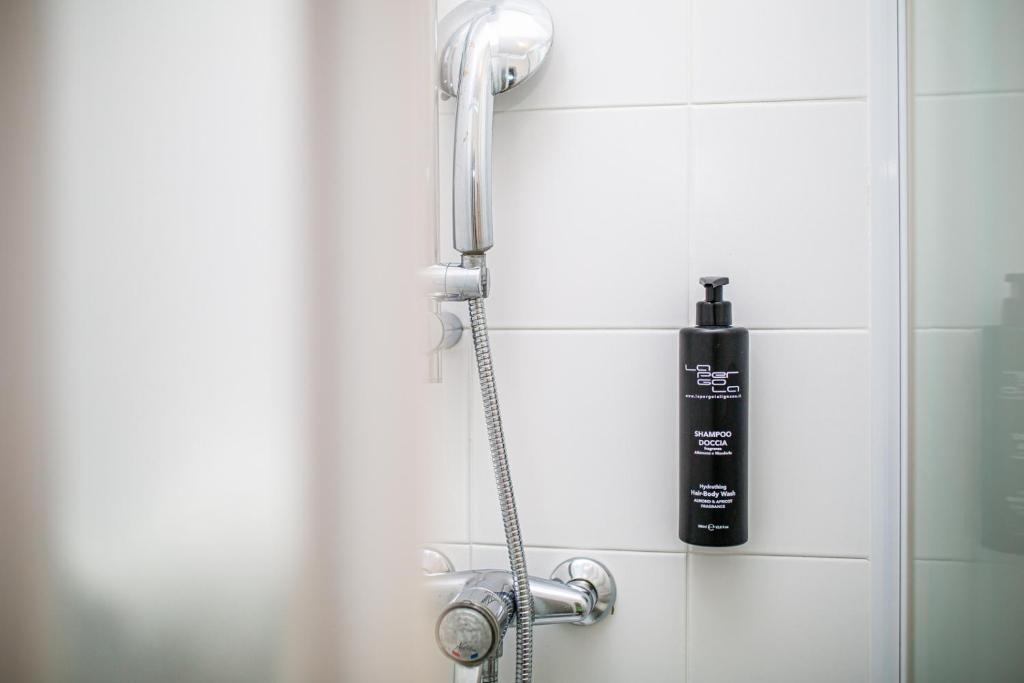 une douche avec une bouteille noire sur le mur dans l'établissement Hotel La Pergola Dependance, à Lignano Sabbiadoro 25 autres photos