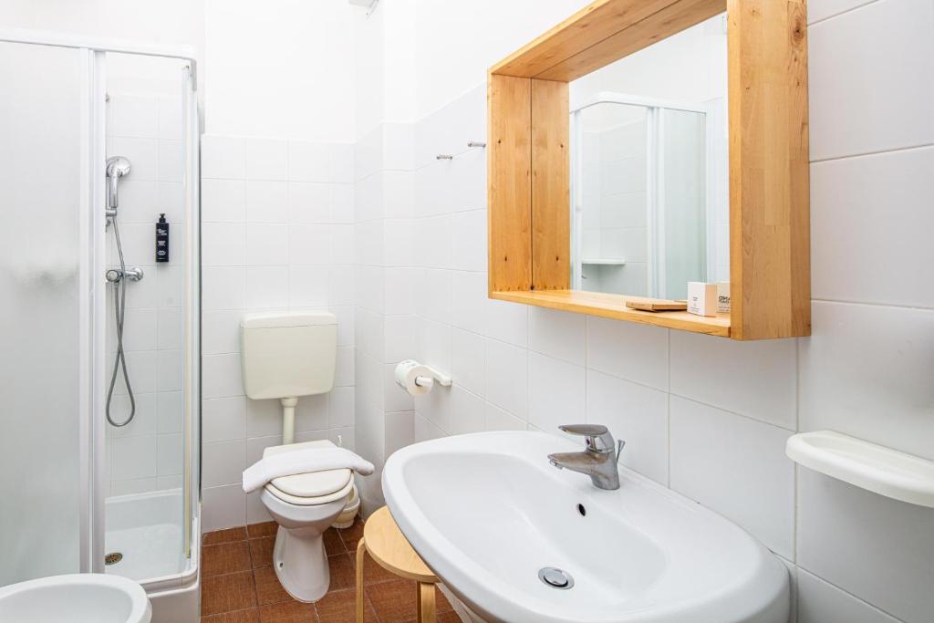 une salle de bain avec un lavabo, des toilettes et un miroir dans l'établissement Hotel La Pergola Dependance, à Lignano Sabbiadoro