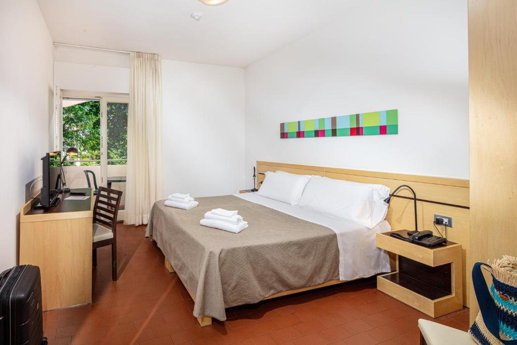 une chambre avec un lit, un bureau et une télévision dans l'établissement Hotel La Pergola Dependance, à Lignano Sabbiadoro