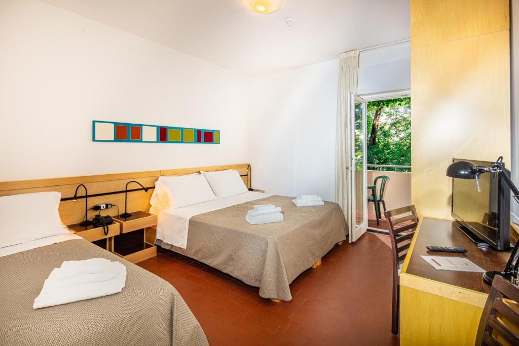 une chambre d'hôtel avec deux lits et une télévision dans l'établissement Hotel La Pergola Dependance, à Lignano Sabbiadoro