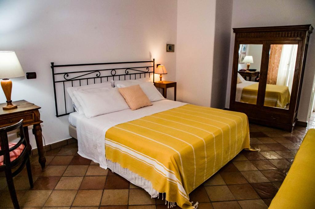 - une chambre avec un lit doté d'une couverture jaune et d'un miroir dans l'établissement Albergo Boutique Casajanca, à Canneto