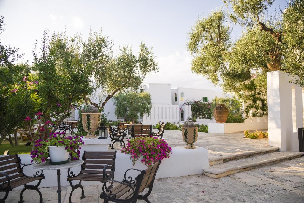 une terrasse avec des chaises, des tables et des fleurs dans l'établissement Masseria Il Melograno, à Monopoli 142 autres photos