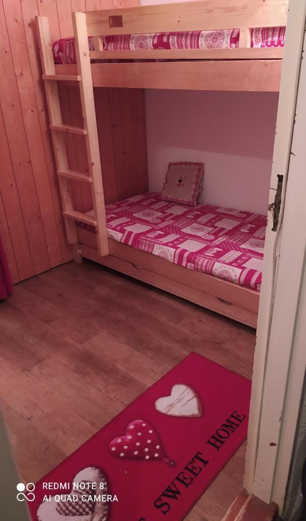 Cette petite chambre comprend 2 lits superposés et un tapis rouge. dans l'établissement Arcs 1800 Belles Challes Studio 5 personnes, à Arc 1800