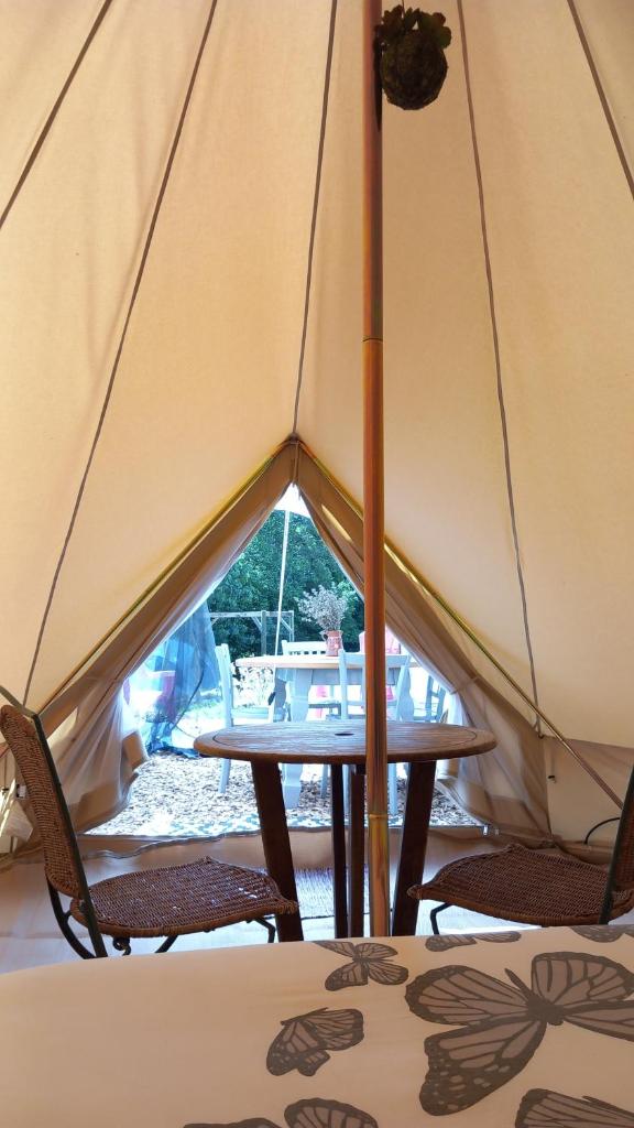 une tente avec 2 chaises et une table. dans l'établissement Tente insolite en pleine nature, à Tréduder