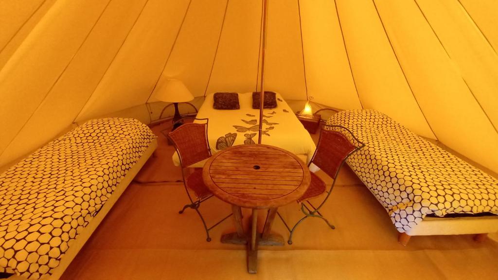 une chambre avec une table et des chaises dans une tente dans l'établissement Tente insolite en pleine nature, à Tréduder