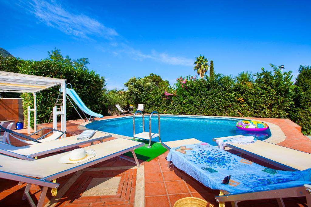 une piscine avec un toboggan et deux chaises longues dans l'établissement Villa Amore seaview pool garden & SPA, à Castellammare di Stabia