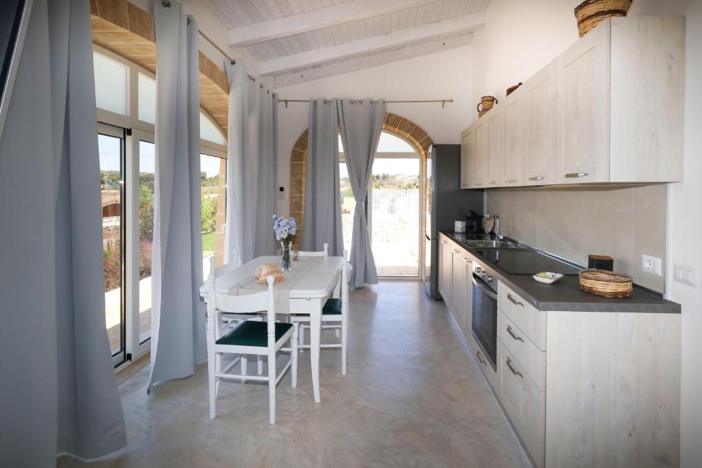 une cuisine avec des armoires blanches et une table et des chaises dans l'établissement Villa Brezza dello Ionio, à Marina di Pescoluse