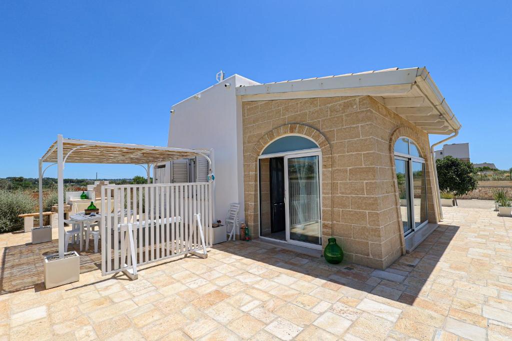 un bâtiment avec une terrasse dotée d'une table et d'une clôture dans l'établissement Villa Brezza dello Ionio, à Marina di Pescoluse