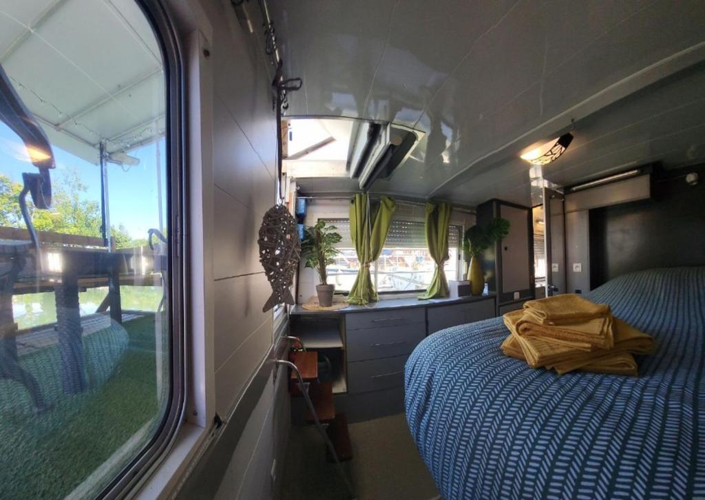 - une chambre avec un lit et une fenêtre dans un coin salon dans l'établissement Logement entier sur bateau, à Montech