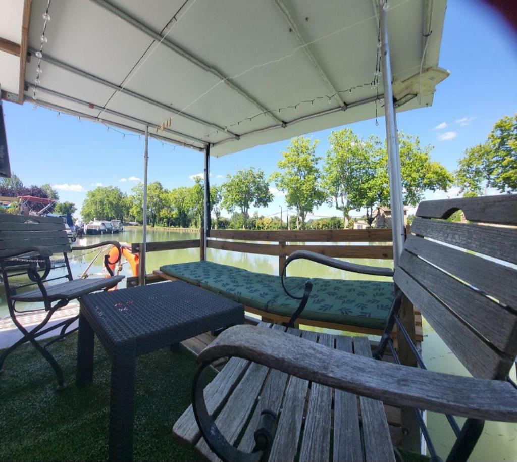 - une terrasse couverte avec des bancs, une table et un parasol dans l'établissement Logement entier sur bateau, à Montech